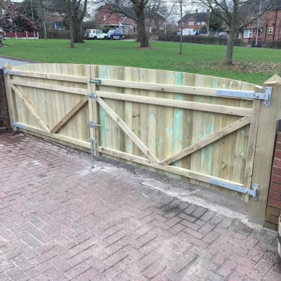 Double gates hung on wooden gate posts by a shaw garden structures