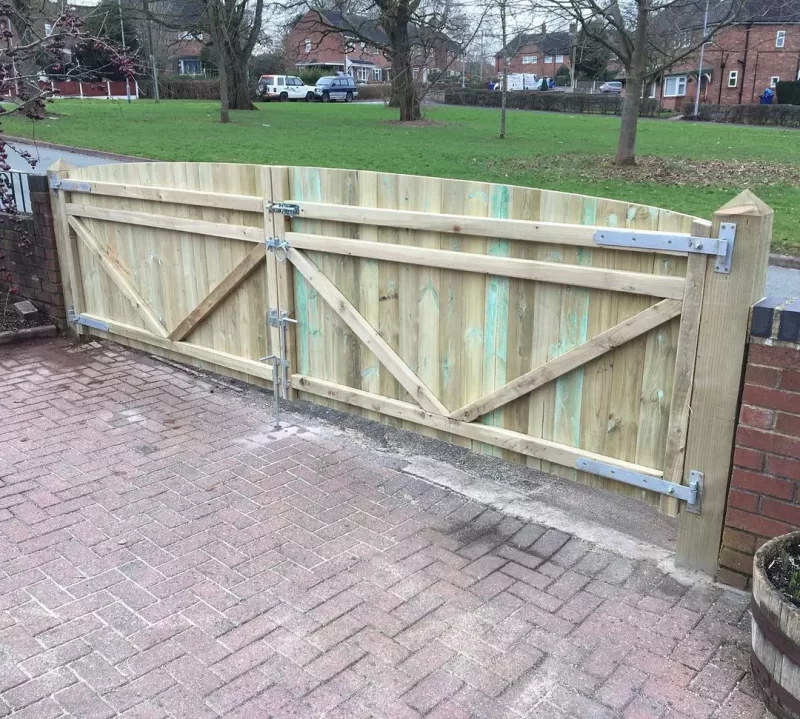 Double gates hung on wooden gate posts by a shaw garden structures